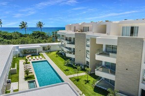 Ein modernes Hotel mit Schwimmbad, mehreren Balkonen und Meerblick.