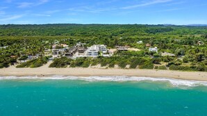Une zone côtière comprenant une plage, un ensemble de logements et, en arrière-plan, une colline boisée.