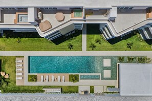 Eine Vogelperspektive eines modernen Hotels mit Schwimmbad, Sitzgelegenheiten im Freien und einem gepflegten Rasen.