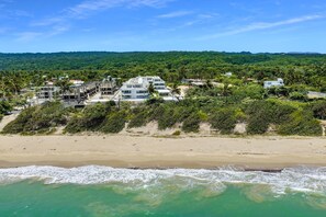 Ein direkt am Strand gelegenes Anwesen mit mehreren Gebäuden, einem Sandstrand und Blick auf das Meer.