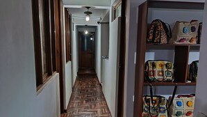 Un corridoio con pavimento in legno, una ventola a soffitto e uno scaffale con borse.