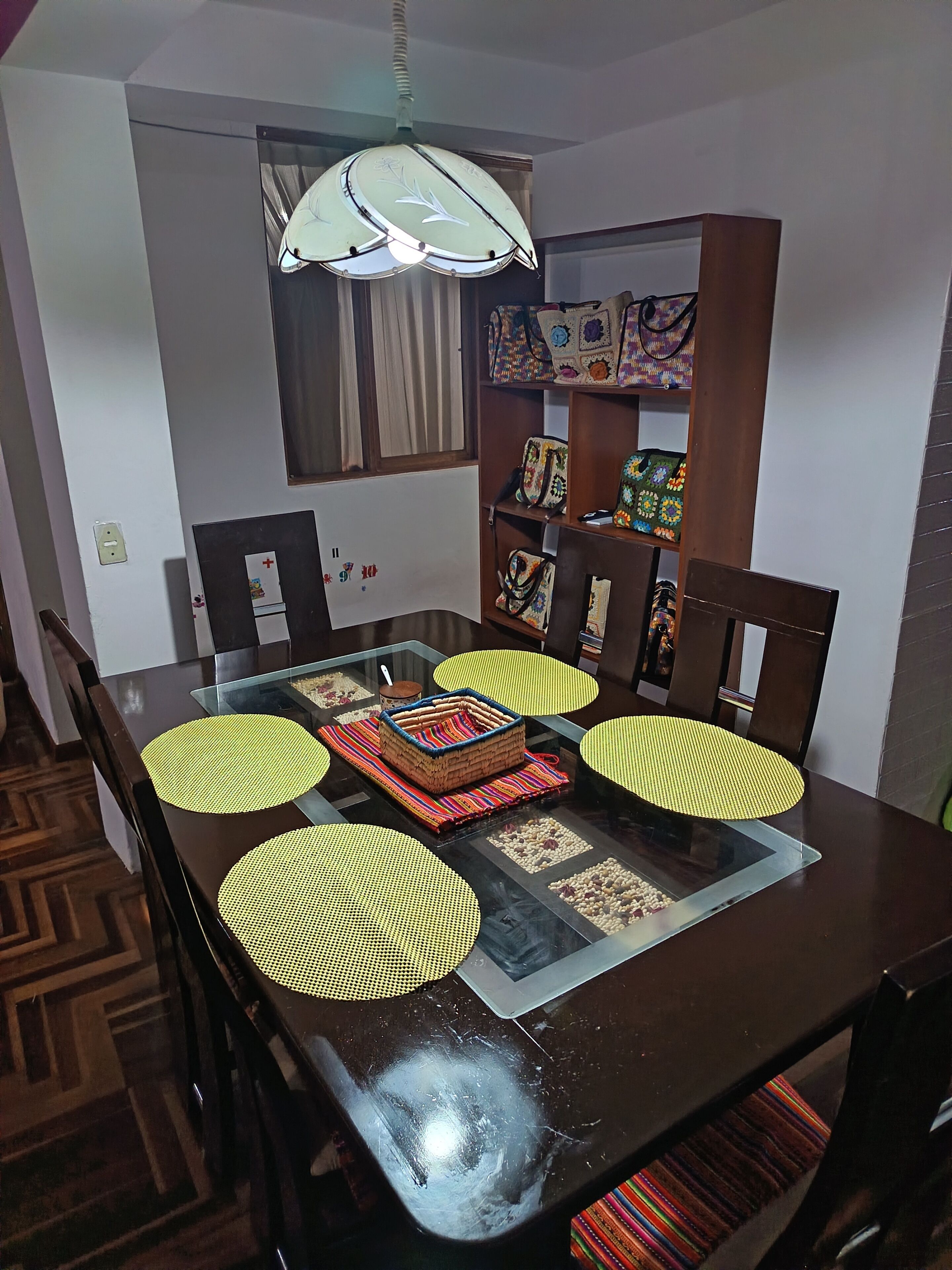 A dining area with a glass table, chairs, a decorative centerpiece, and a ceiling fan.