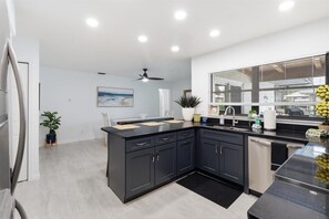 A modern kitchen with dark cabinetry, a black countertop, and a built-in dishwasher. - Waterfront 3BR/2BA 5 beds, Dock, Kayaks, Scalloping & Manatees (Crystal River)