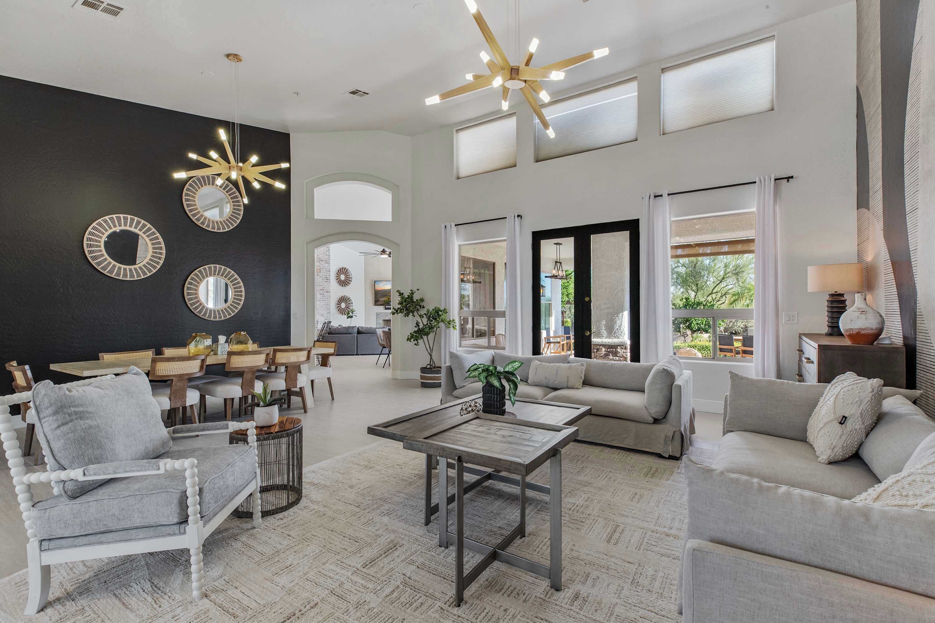 A spacious living area with a high ceiling, modern furniture, and decorative mirrors.