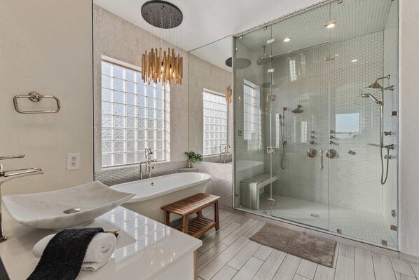 Ein modernes Badezimmer mit einer freistehenden Badewanne, einer Duschkabine und einer hölzernen Sitzbank.