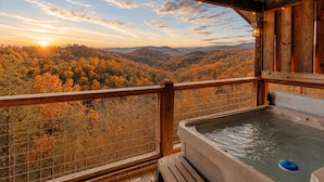 A wooden deck with a hot tub and a view of autumn foliage. - Honeymoon VIEW! Beautiful romantic cabin, great location & hot tub w/epic view! (Sevierville)