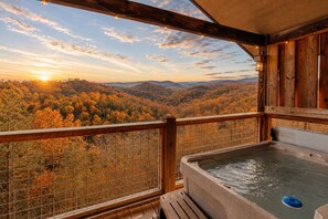 A wooden deck with a hot tub and a view of autumn foliage. - Honeymoon VIEW! Beautiful romantic cabin, great location & hot tub w/epic view! (Sevierville)