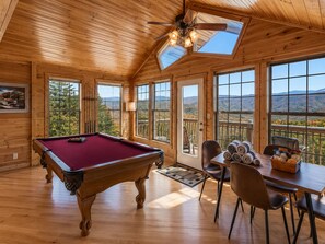 A wooden cabin with a pool table, dining area, and large windows offering mountain views. - Honeymoon VIEW! Beautiful romantic cabin, great location & hot tub w/epic view! (Sevierville)