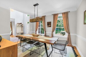 A dining area with a wooden table, wire chairs, and a hanging light fixture. - Private Oasis Retreat with a Pool (Unknown)