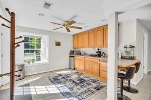 Una cocina moderna con armarios de madera, ventilador de techo, microondas empotrado y cafetera.