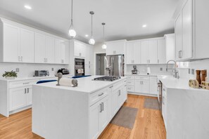 A modern kitchen with white cabinetry, a central island, and a built-in oven. - Private Oasis Retreat with a Pool (Fairfax)