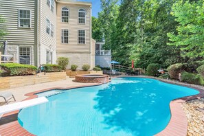 A swimming pool with a brick edge, surrounded by a wooden deck and a brick wall. - Private Oasis Retreat with a Pool (Unknown)