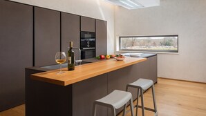 Eine moderne Küche mit einer Holzinsel, Barhocker, einer Weinflasche und einer Obstschale.