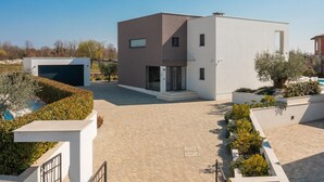 Ein modernes, zweistöckiges Gebäude mit flachem Dach, einer Garage und einem gepflasterten Innenhof.