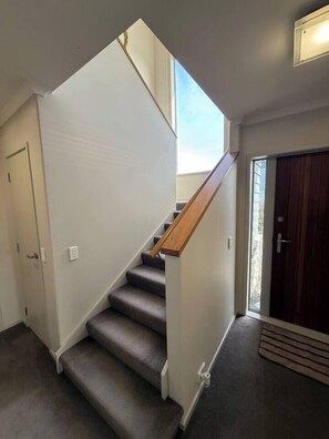 Eine Treppe mit Teppichstufen, einem Holzgeländer und einer Tür am oberen Ende.