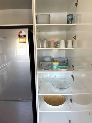 Eine Küche mit einem Edelstahl-Kühlschrank, einer eingebauten Schranke mit Gläsern, Tellern und Schüsseln.