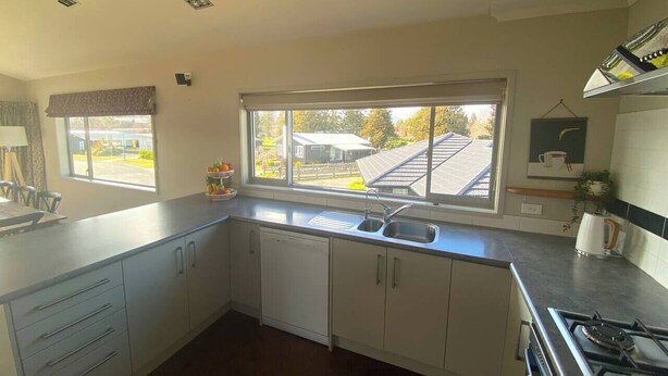 A kitchen with a window, sink, cabinets, and a stove. - 53 Snowmass Dr - Ohakune Retreat w/ Ruapehu View (Ohakune)