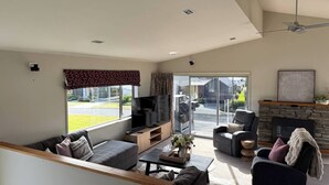 A modern living room with a sofa, armchairs, a coffee table, and a fireplace. - 53 Snowmass Dr - Ohakune Retreat w/ Ruapehu View (Ohakune)