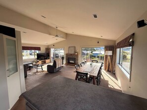 A spacious living area with a large dining table, a fireplace, and a television. - 53 Snowmass Dr - Ohakune Retreat w/ Ruapehu View (Ohakune)