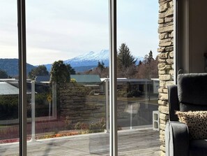 Ein Zimmer mit großem Fenster mit Blick auf einen Berg und eine Steinmauer.
