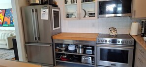 Eine moderne Küche mit Edelstahlgeräten, darunter ein Kühlschrank, ein Backofen und eine Mikrowelle.