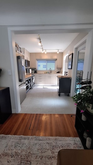 A modern kitchen with a central island, built-in appliances, and a view to the dining area. - Family Cottage-House in Scenic James Bay, Victoria: 1 Blk to Ocean & Ogden Pt! (Victoria)