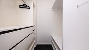 A narrow walk-in closet with white cabinetry, a black hanger, and a black carpeted floor. - Elmrise in Elsternwick (Saint Kilda East)