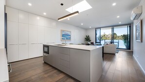 A modern kitchen with a central island, white cabinetry, and a large window offering a view of the outdoors. - Elmrise in Elsternwick (Saint Kilda East)