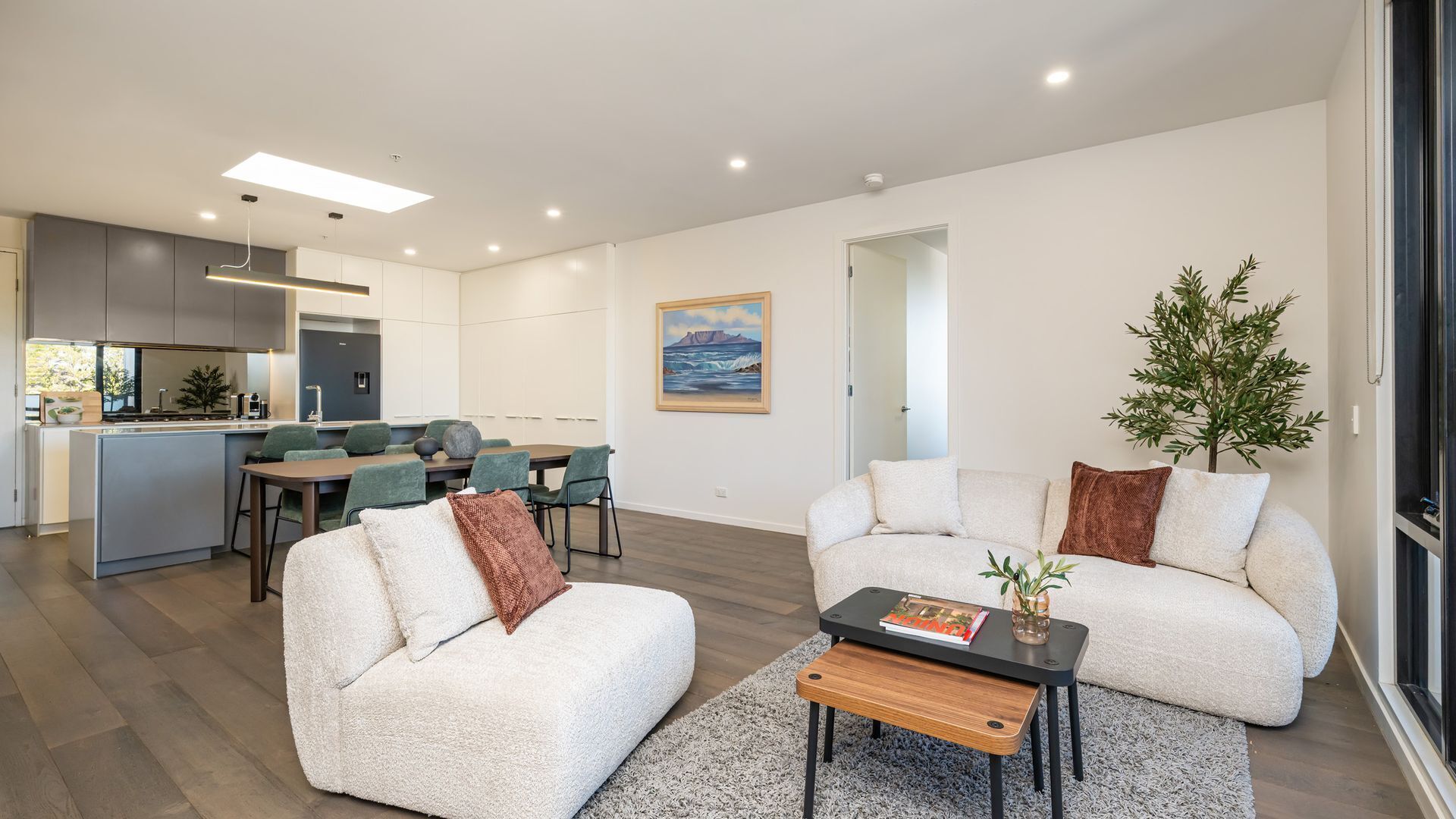 Uma sala de estar moderna com um sofá, mesa de centro e um espaço de jantar com cadeiras e uma mesa.