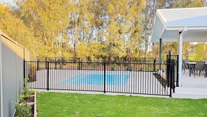 En trädgård med en pool, ett inhägnat område och en täckt uteplats.
