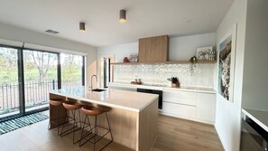 Eine moderne Küche mit einer großen Kochinsel, Barhocker und Blick ins Freie.