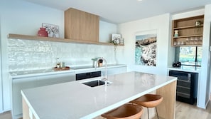 A modern kitchen with a central island, stainless steel appliances, and a view of the outdoors. - The Silverwoods Retreat (Yarrawonga)