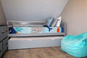 Ein Stockbett mit unterer Ablage, ein blaugrüner Sitzsack und ein Wandregal.
