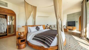 Een ruime slaapkamer met een groot bed, houten hoofdeinde en een baldakijn.