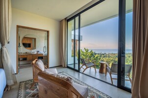Un dormitorio moderno con un amplio ventanal corredera que da a un balcón con vistas al océano.