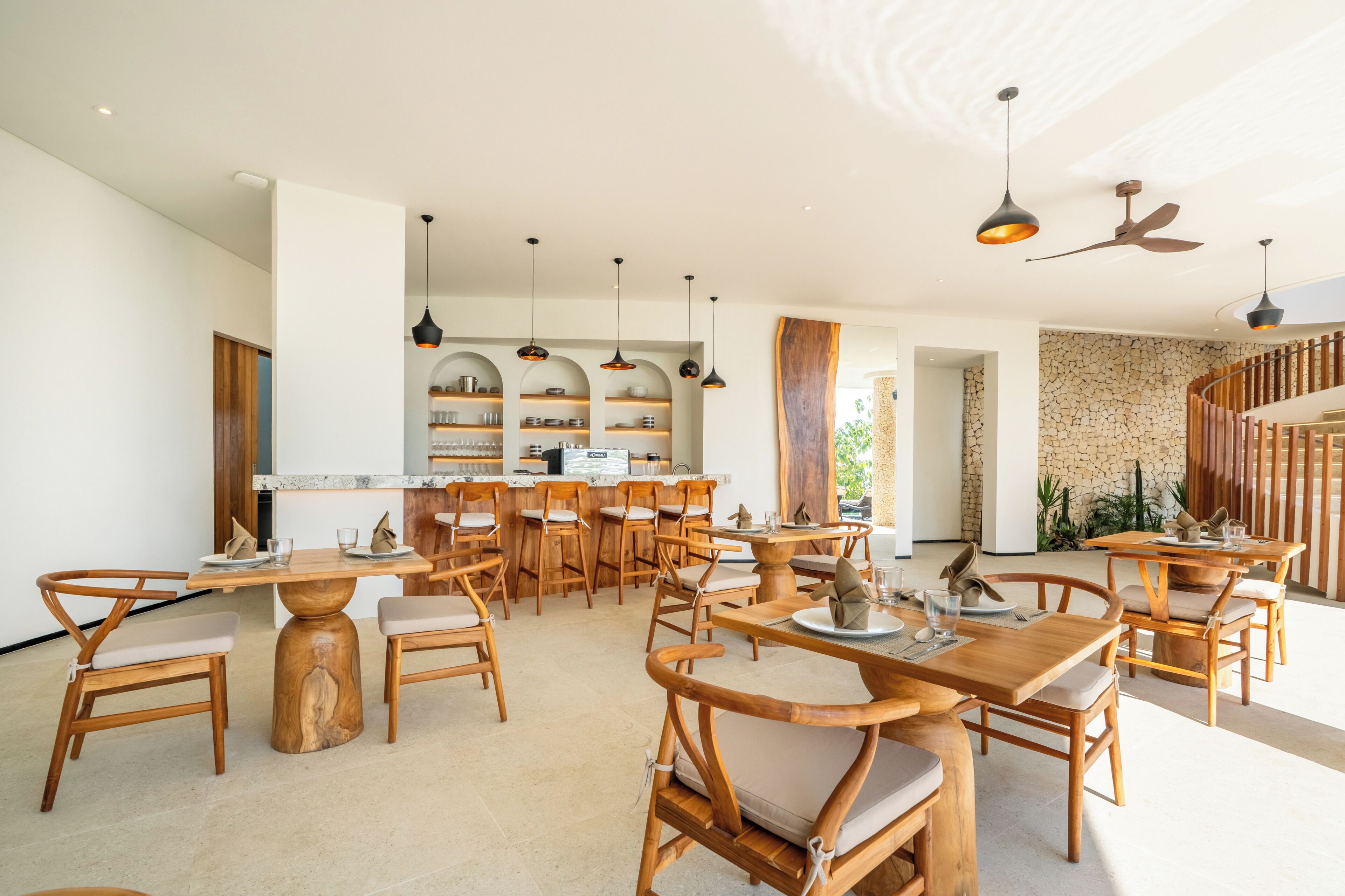 A spacious dining area with wooden furniture and pendant lighting.