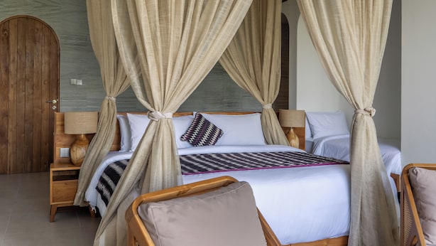 A bedroom with a four-poster canopy bed, wooden furniture, and a large wooden door. - Villa Karilla (Penida Island)