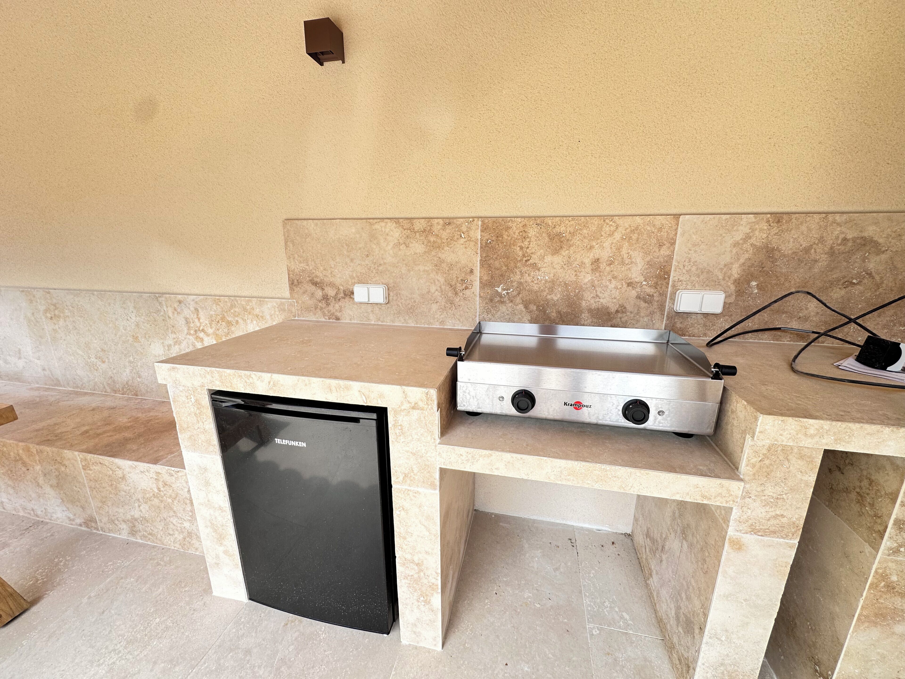A compact kitchen area with a built-in dishwasher, a stainless steel cooking range, and a countertop.