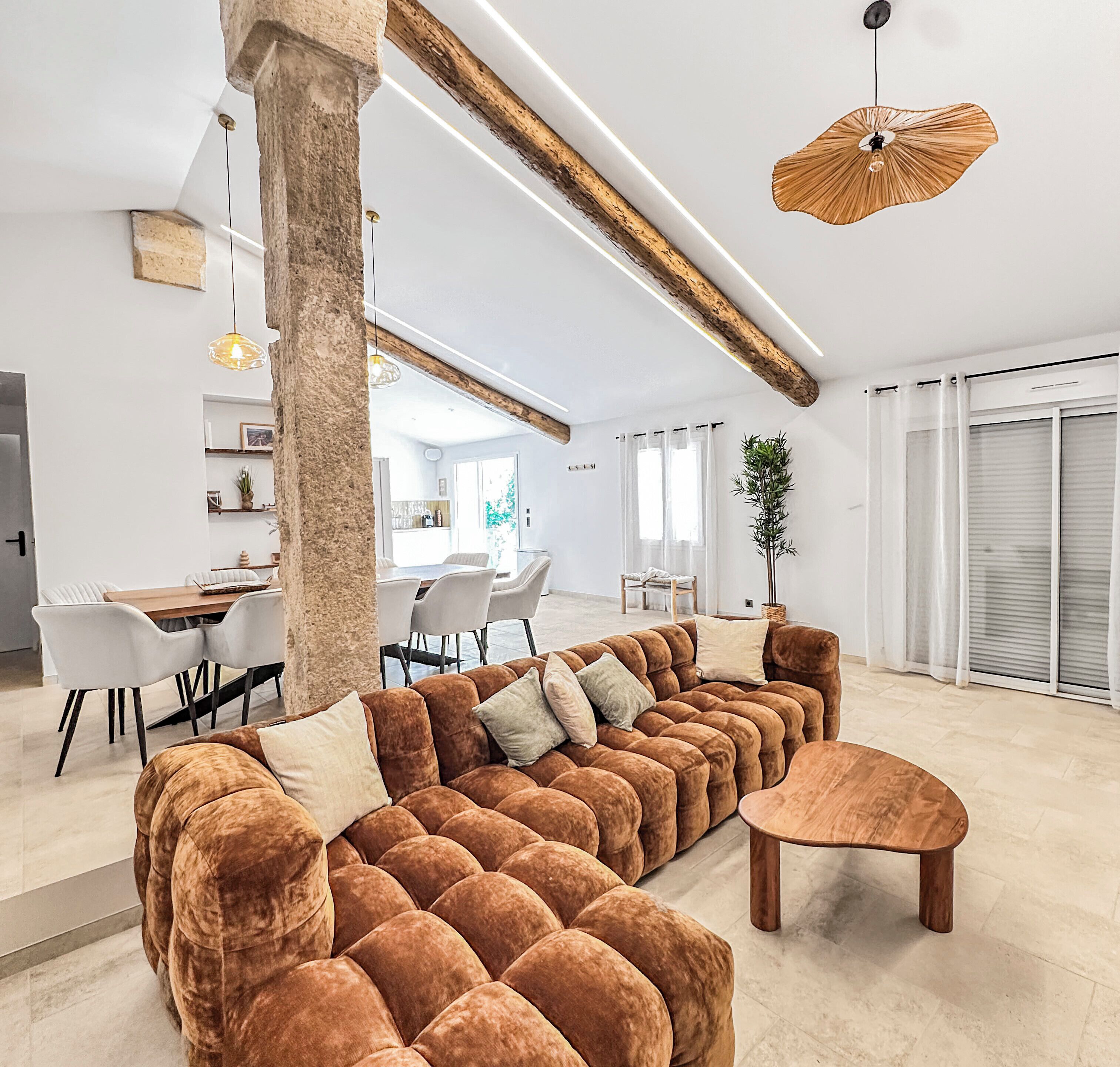 A modern living room with a large sectional sofa, a wooden coffee table, and a dining area with a white table and chairs.