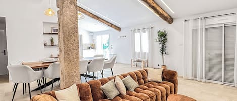 A modern living room with a large sectional sofa, a wooden coffee table, and a dining area with a white table and chairs.