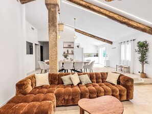 A modern living room with a brown sofa set, a wooden coffee table, and a dining area in the background.