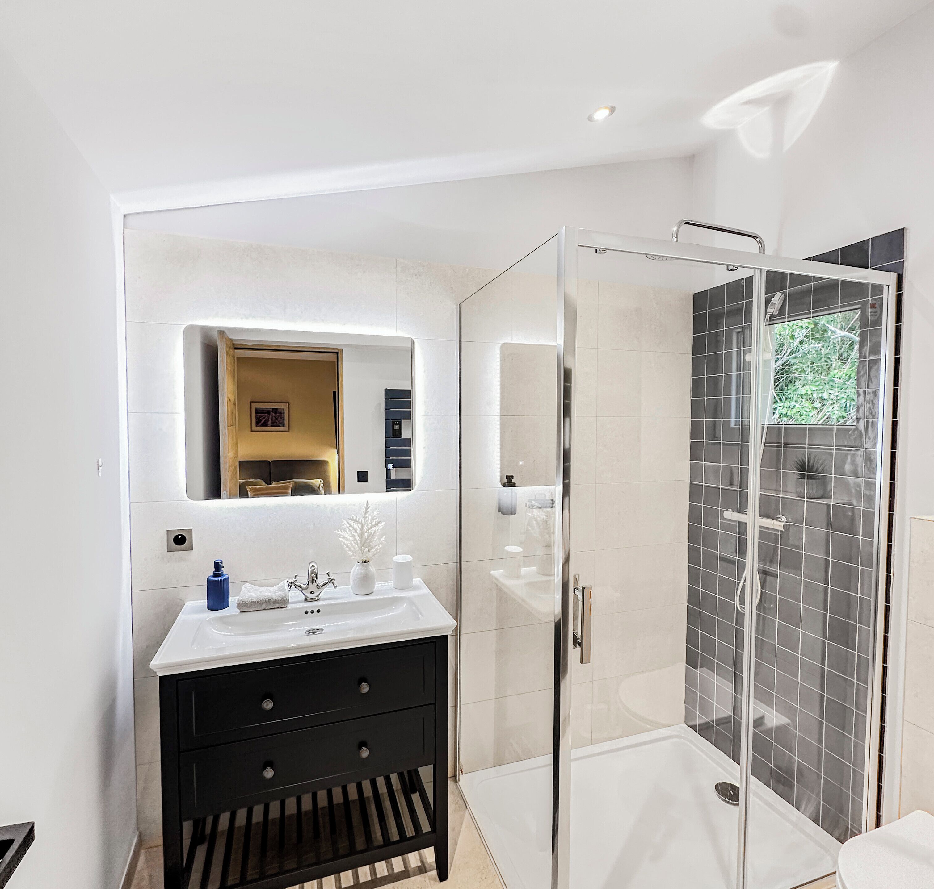 A modern bathroom with a glass-enclosed shower, a vanity with a mirror, and a sink.