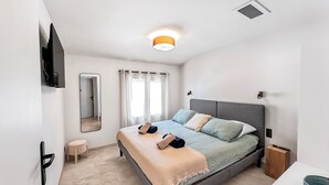 Ein modernes Schlafzimmer mit einem Bett, einem Nachttisch und einem an der Wand montierten Fernseher.