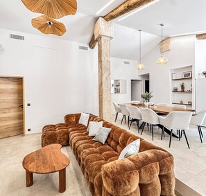 A modern living room with a sectional sofa, a wooden coffee table, and a dining area with a wooden table and chairs.