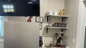 A kitchen with a refrigerator, microwave, coffee maker, wine rack, and various kitchen utensils. - Equestrian cottage— country living in the city (Aiken)