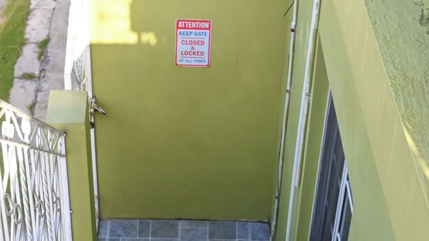 A set of stone stairs leading to a green door with a sign that reads 'ATTENTION KEEP GATE CLOSED & LOCKED AT ALL TIMES.' - 2-bedroom apartment in fantastic Montego Bay with AC (Montego Bay)
