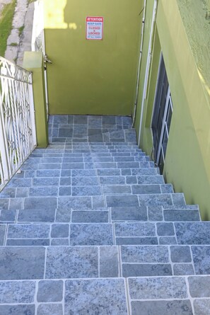 A set of stone stairs leading to a green door with a sign that reads 'ATTENTION KEEP GATE CLOSED & LOCKED AT ALL TIMES.' - 2-bedroom apartment in fantastic Montego Bay with AC (Montego Bay)
