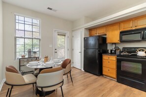 Eine Küche mit Esstisch, Stühlen, Kühlschrank, Backofen, Mikrowelle und Holzschränken.
