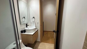 A modern bathroom with a white sink, mirror, and wooden vanity. - w* | Enchanting Loft in the Heart of Roma Sur (Ciudad de México)