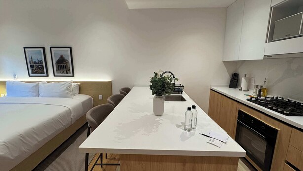 A modern hotel room with a bed, a dining table, a kitchen area, and a small plant on the table. - w* | Enchanting Loft in the Heart of Roma Sur (Ciudad de México)